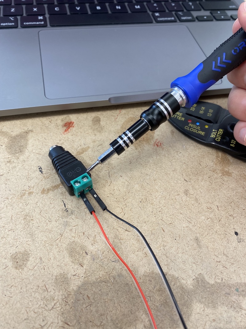 Tightening the screws on the powerjack to secure the wires
